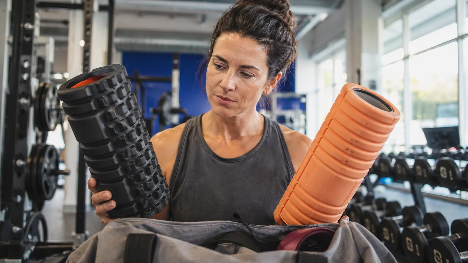 Foam roller resting against a hotel room bed next to a travel bag